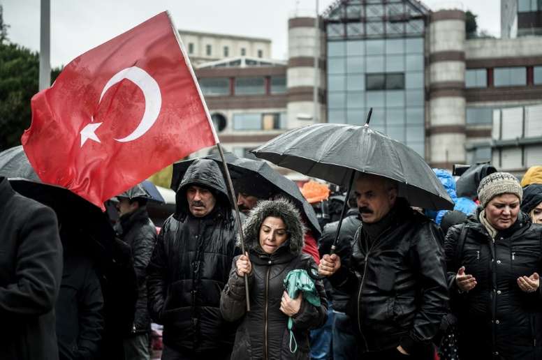 People hold a Turkish flag at the site of the December 10 blasts near Besiktas Vodafone Arena. AFP