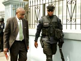 Former FIFA vice president Jack Warner (L) is escorted by a police officer to the Port-of-Spain Magistrates court in Trinidad, for an extradition hearing on July 27, 2015