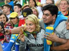 A Germany player holds up her gold medal as she poses for a selfie with a fan. AFP