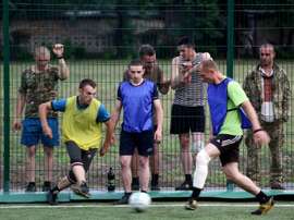 Ukrainian soldiers watch their colleagues play during a football match against a team of local residents, in the government-held town of Kurakhove, eastern Donetsk region