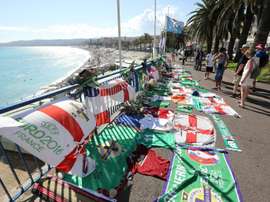 People stand next to tributes for a Northern Ireland fan who died during the Euro 2016 football tournament in Nice