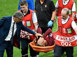 Portugals forward Cristiano Ronaldo is comforted by Portugals coach Fernando Santos as he is carried on a stretcher off the pitch by team medics after an injury following a clash with Frances forward Dimitri Payet during the Euro 2016 final