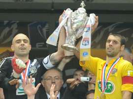 Les capitaines de Lyon et de Quevilly brandissent ensemble le trophée de la Coupe de France. AFP