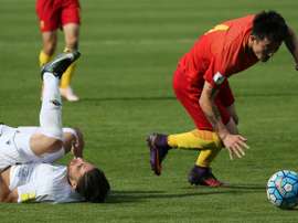 Le Chinois Zhipeng trébuche sur l'Iranien Jahanbakhsh au cours du match de qualification. AFP