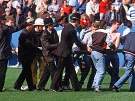 Des policiers transportent un supporter blessé dans le stade de Hillsborough. AFP