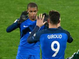 Olivier Giroud croise Kylian Mbappé lors de son remplacement. AFP