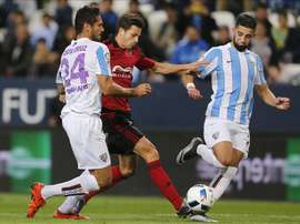 El defensa del Mirandés Ernesto Galán (c) lucha por el balón ante los jugadores del Málaga, el delantero paraguayo Roque Santa Cruz (i) y el centrocampista marroquí Adname Tighadouini, durante el partido de vuelta de los dieciseisavos de la Copa del Rey que se jugó en el estadio de la Rosaleda en Málaga. EFE
