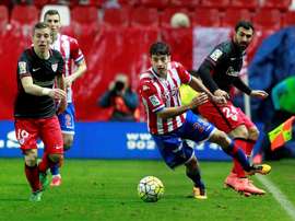 El centrocampista del Sporting de Gijón Jonathan Rodríguez (c) con el balón ante los jugadores del Athletic Iker Muniain (i) y Mikel Balenziaga (d), durante el partido de la jornada vigésima octava de Liga de Primera División celebrado en el estadio del Molinón de Gijón. EFE/Archivo