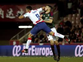 El delantero argentino del Granada Ezequiel Ponce (primer término) golpea al defensa del Osasuna Oier Sanjurjo en el estadio Nuevo Los Cármenes. EFE