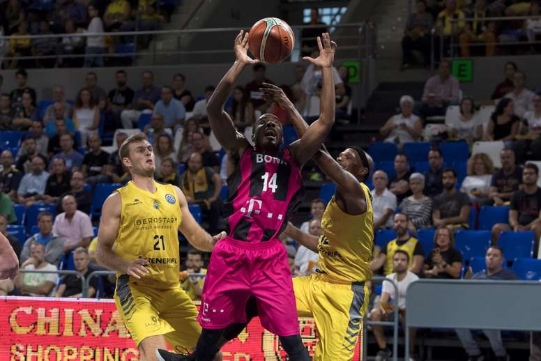 El base estadounidense del Telekom Bonn, Josh Mayo (c), lucha por un rebote ante la oposición del ala pívot del Iberostar Tenerife, el Tim Abromaitis (i) y del escolta del Iberostar Tenerife, Thadd McFadden (d), durante el partido de la Liga de Campeones que se disputa hoy en el pabellón Santiago Martín de La Laguna (Tenerife). EFE