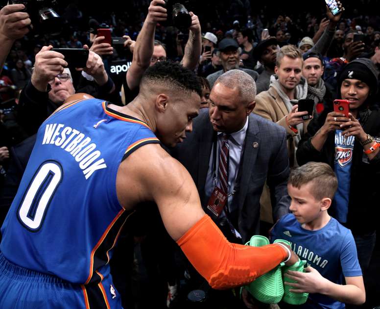 El jugador Russell Westbrook (i) de Oklahoma City Thunder le entrega sus zapatos a un aficionado al final del partido de la NBA entre Oklahoma City Thunder y Brooklyn Nets disputado este miércoles en el Barclays Center en Brooklyn, Nueva York (Estados Unidos). EFE