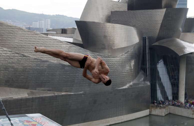 El clavista ucraniano Oleskiy Prygorov en la primera ronda de la competición ante el museo Guggenheim de Bilbao, de saltos de altura de clavadistas más extrema, el Red Bull Cliff Diving, desde el puente de La Salve sobre la ría de Bilbao, el año pasado. EFE/Archivo