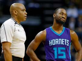 Kemba Walker (d) de Hornets junto a un juez durante un juego de la NBA. EFE/Archivo