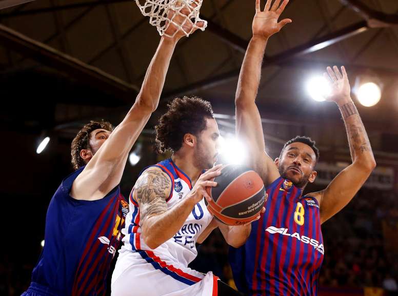 El escolta estadounidense del Anadolu Efes Shane Larkin (c) entra a canasta defendido por el croata Ante Tomic (i) y el húngaro Adam Hanga, ambos del del FC Barcelona Lassa, durante el tercer partido de cuartos de final de la EurLliga de baloncesto que se juega esta noche en el Palau Blaugrana, en Barcelona. EFE