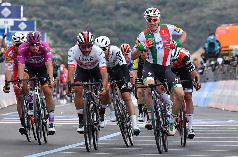 El corredor colombiano Fernando Gaviria del equipo UAE Team Emirates (c-i) y el italiano Elia Viviani del equipo Deceuninck-Quick Step (c-d) reaccionan tras cruzar la línea de meta de la tercera etapa del Giro de Italia, de 220 kilómetros, comprendida entre Vinci y Orbetello, este lunes en Italia. EFE