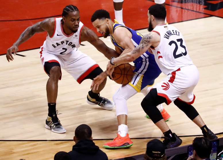 El jugador de los Warriors de Golden State Stephen Curry (c) recibe presión de sus rivales de los Raptors de Toronto Leonard (i) y Fred VanVleet (d). EFE
