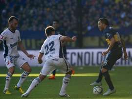 Carlos Tevez (R) vies for the ball with Adrian Calello (C) and defender Mariano Uglessich during their Argentina First Division football match in Buenos Aires, Argentina, on July 18, 2015.