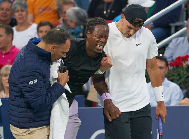 Gael Monfils (c) de Francia, se queja de dolor por una lesión, mientras Jack Draper (d) de Reino Unido, y una persona de apoyo médico (i), lo asisten fuera de la cancha, durante el Masters 1.000 de Montreal (Canadá), este 11 de agosto de 2022. EFE/EPA/Andre Pichette