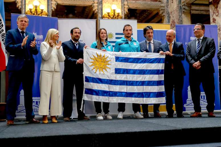 Los deportistas Agustina Modernell y Emiliano Lasa (c) posan con la vicepresidenta de Uruguay, Beatriz Argimón (i), y demás autoridades, tras recibir la bandera nacional previo a su viaje a Asunción para los XII Juegos Suramericanos, durante un acto de despedida hoy, en el Palacio Legislativo, en Montevideo (Uruguay). EFE/Alejandro Prieto