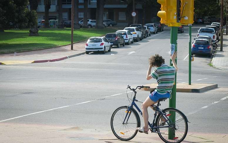 Un ciclista fue registrado este martes, 21 de marzo, al sostenerse de un semáforo en el cruce de una avenida en Montevideo (Uruguay). EFE/Daniela Calone